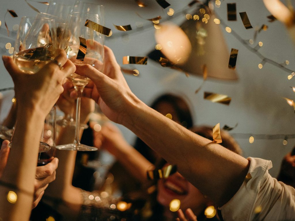 pexels-photo-3171837-3171837 A lively indoor party scene with people toasting champagne glasses amid confetti and warm lights.